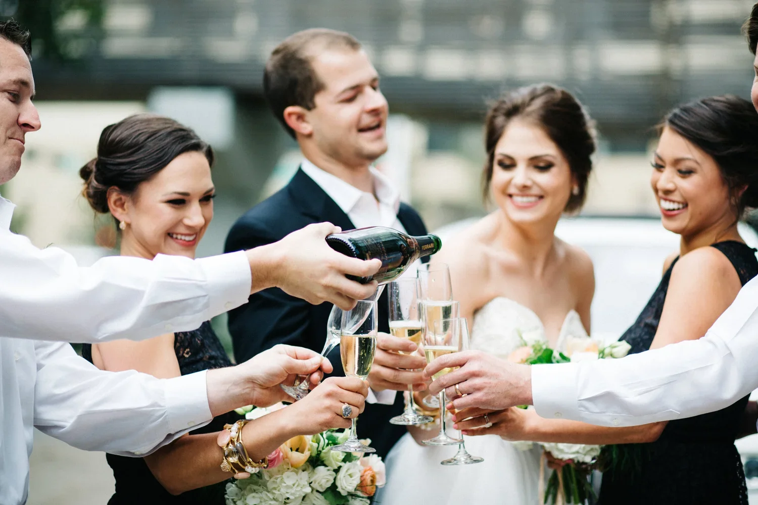 A group of people celebrating at a wedding, pouring champagne into glasses.