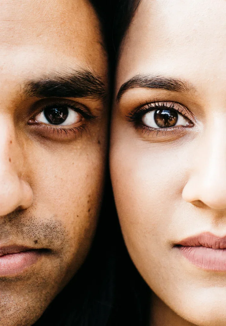 Close-up of a man and woman with their faces touching, showing only the right half of the man's face and the left half of the woman's face, with a focus on their eyes.