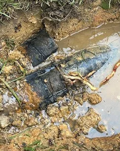 Broken and submerged electrical boxes in muddy water with exposed wires.