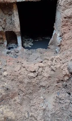 Concrete structure with a dark tunnel entrance, surrounded by dirt and soil.