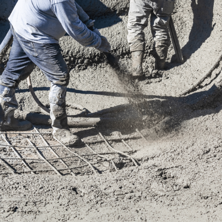 an image of a worker using a shotcrete system including a concrete pumping hose that is pouring gunite or shotcrete from a shotcrete nozzle onto a swimming pool base