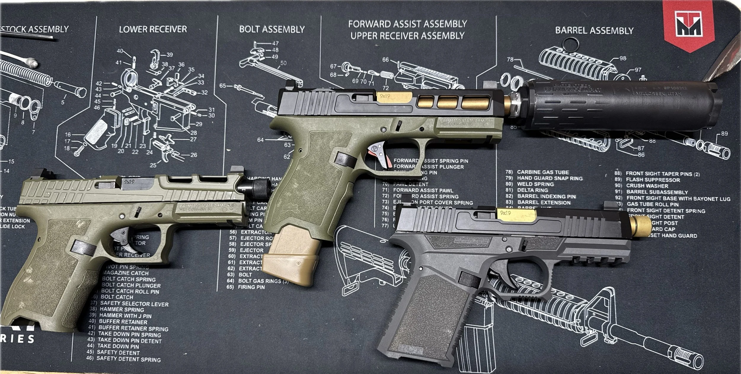Firearms including two pistols and a suppressor on a gun assembly diagram cloth.