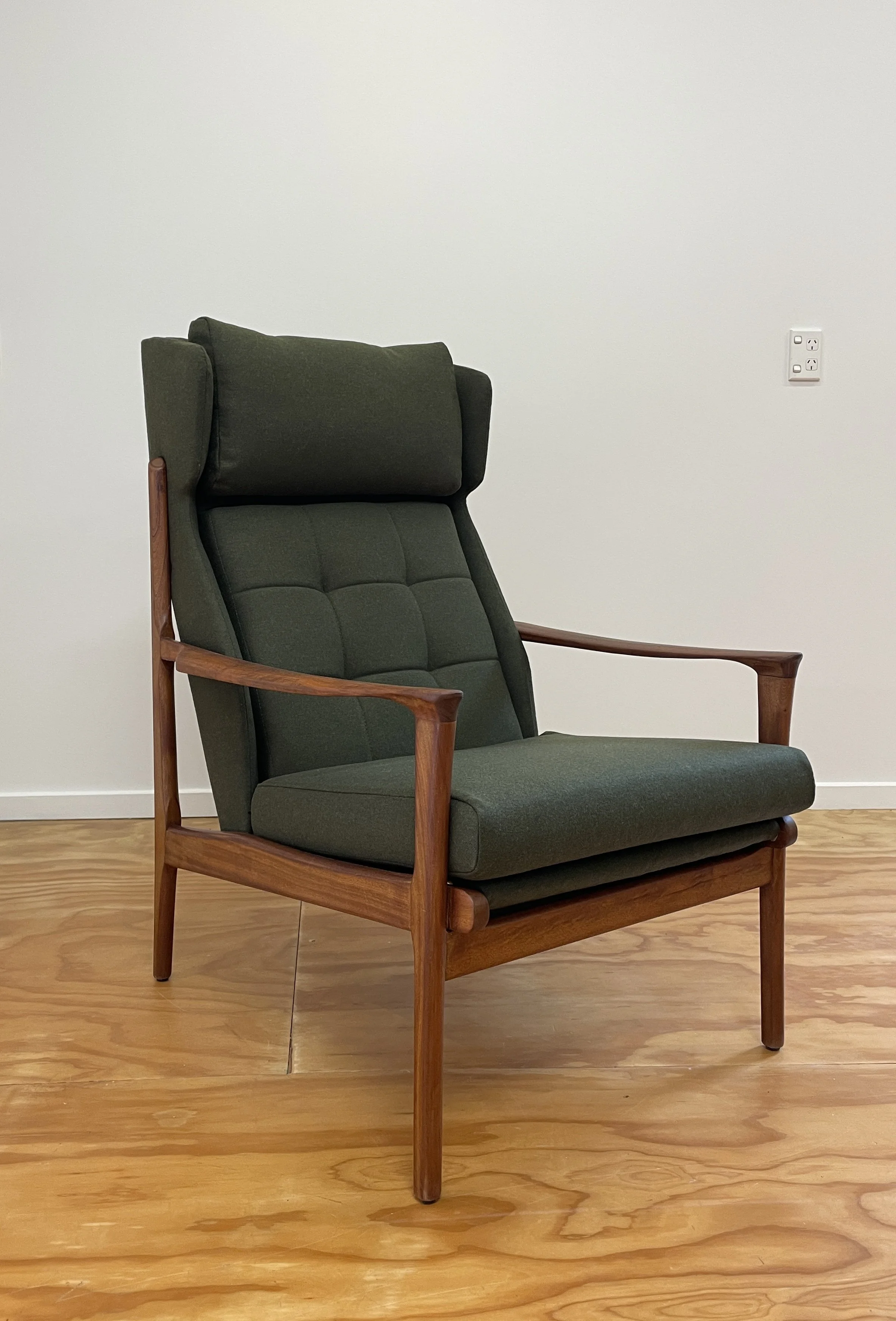 A Fler designed mid-century modern green upholstered armchair with wooden frame and armrests.