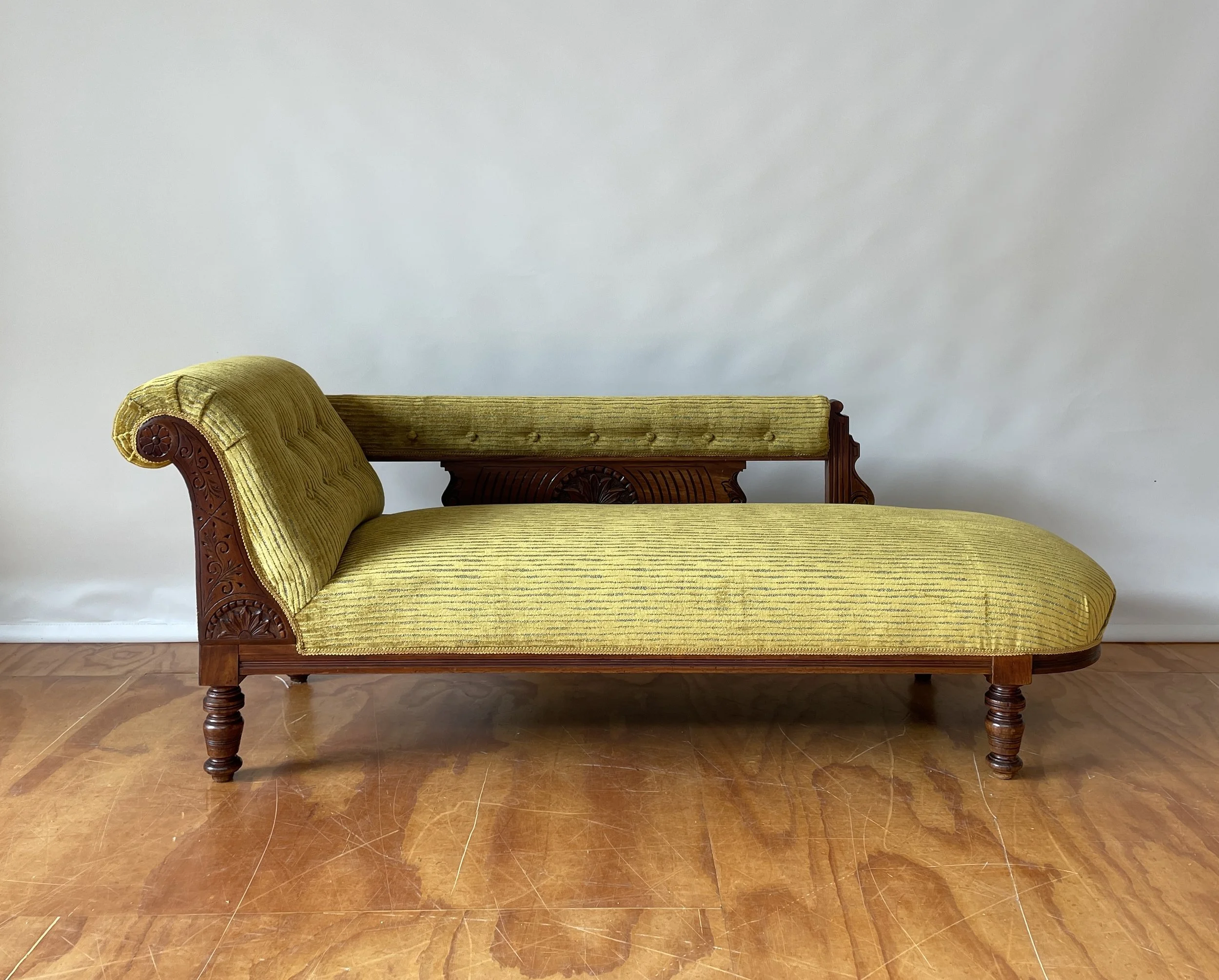 Vintage Victorian-style chaise lounge with yellow-green fabric upholstery and carved wooden frame.