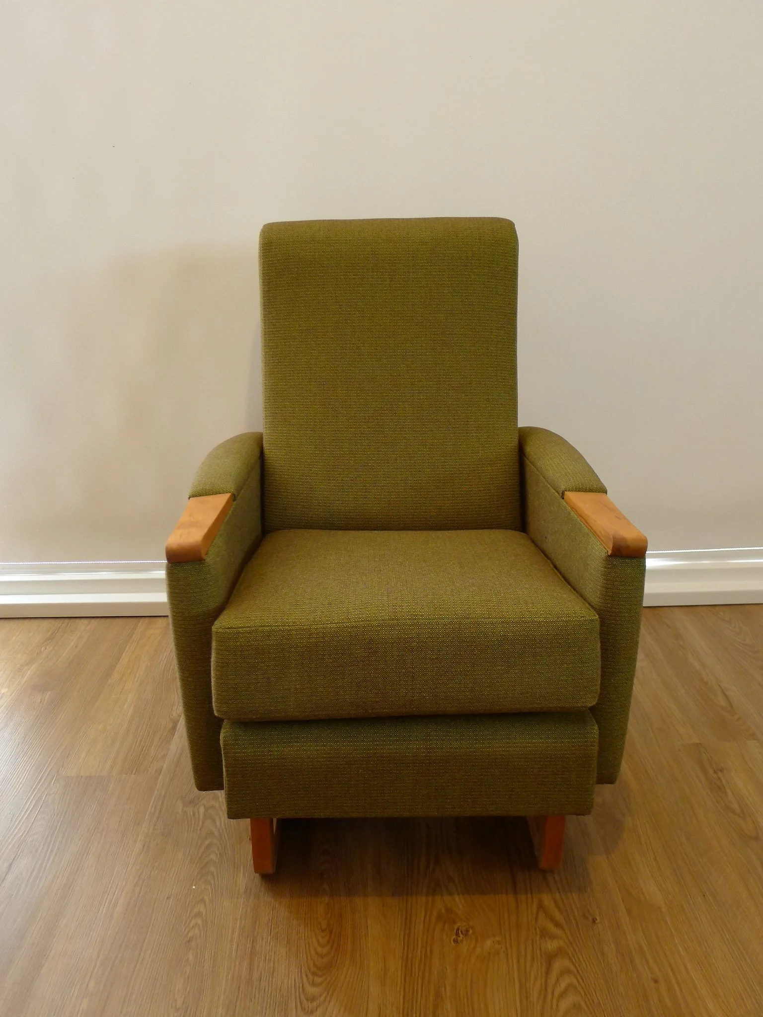 Green upholstered armchair with wooden armrests and legs.
