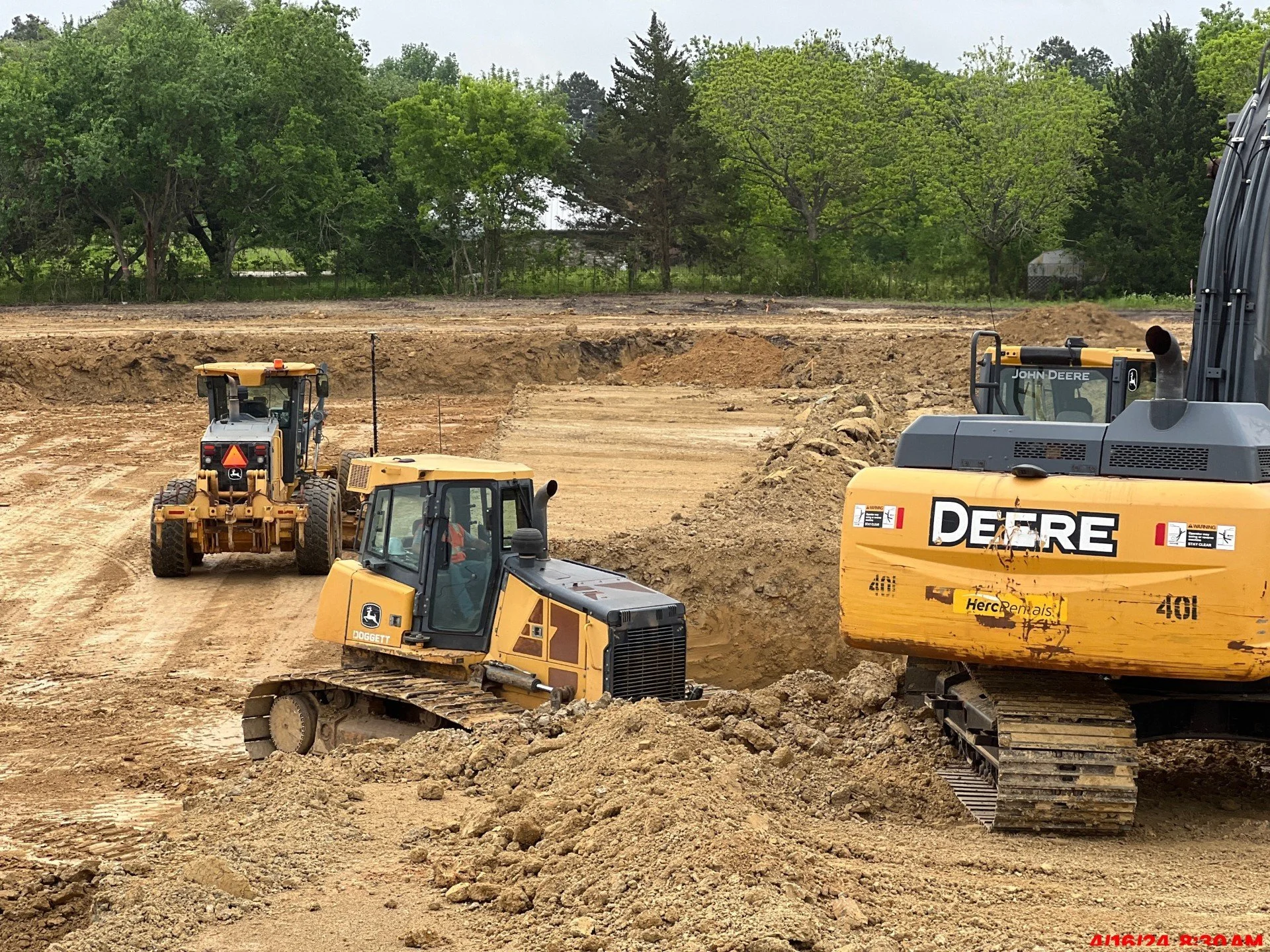 Excavation crew operating heavy equipment for site preparation and dirt work in Willis on a large construction project