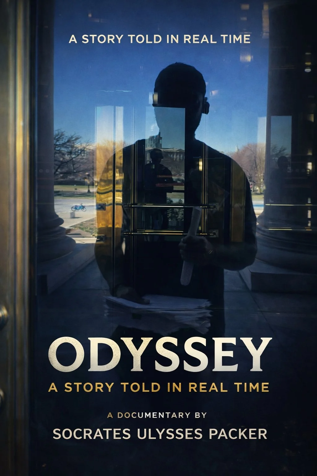 Reflective glass door with text promoting a documentary titled "Odyssey," featuring the subtitle "A story told in real time" and acknowledging filmmaker Socrates Ulysses Packer. The reflection shows a person taking the photo, trees, a bicycle, and a building outside.