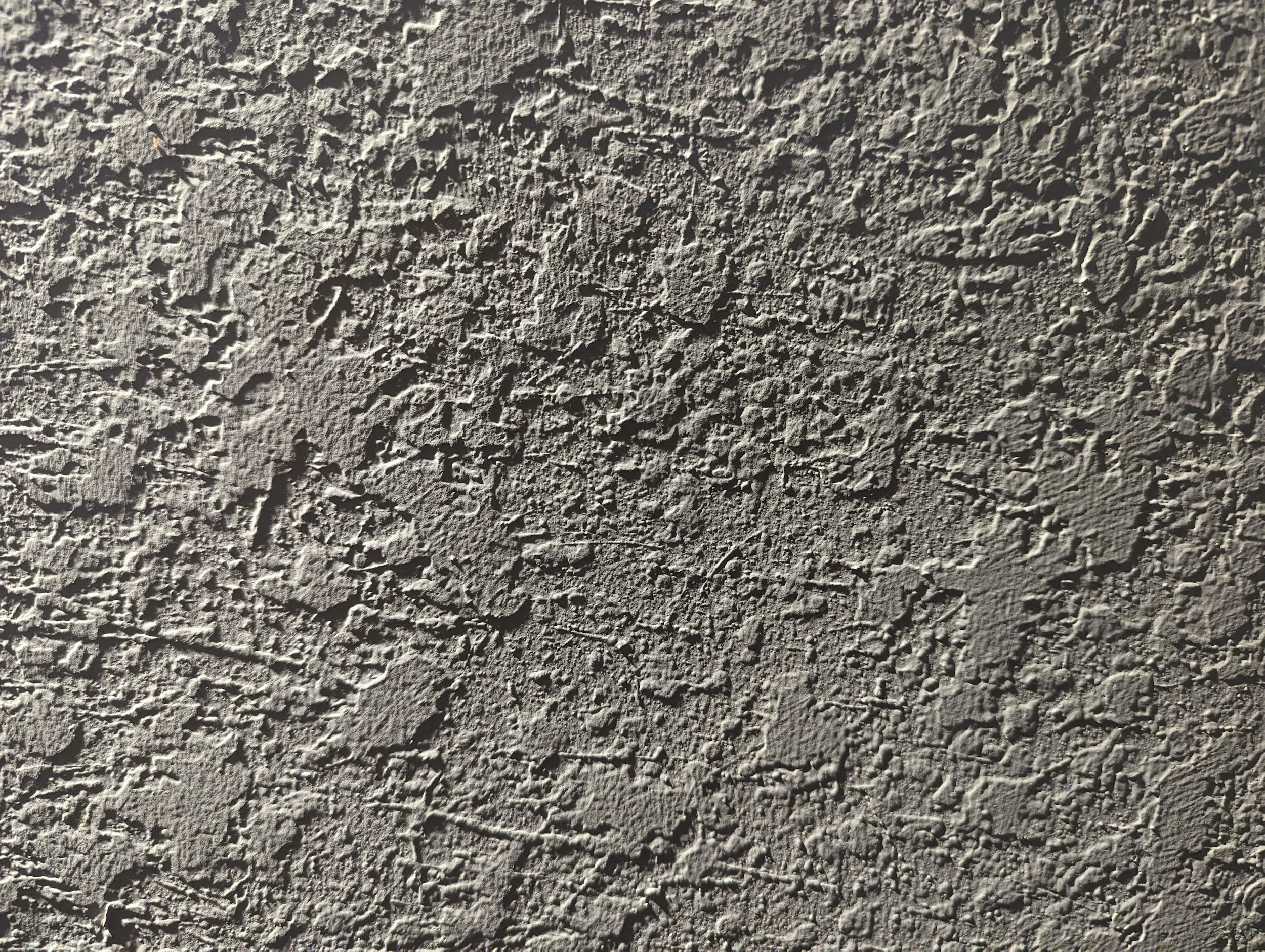 Close-up of a textured concrete wall surface with rough, uneven details.