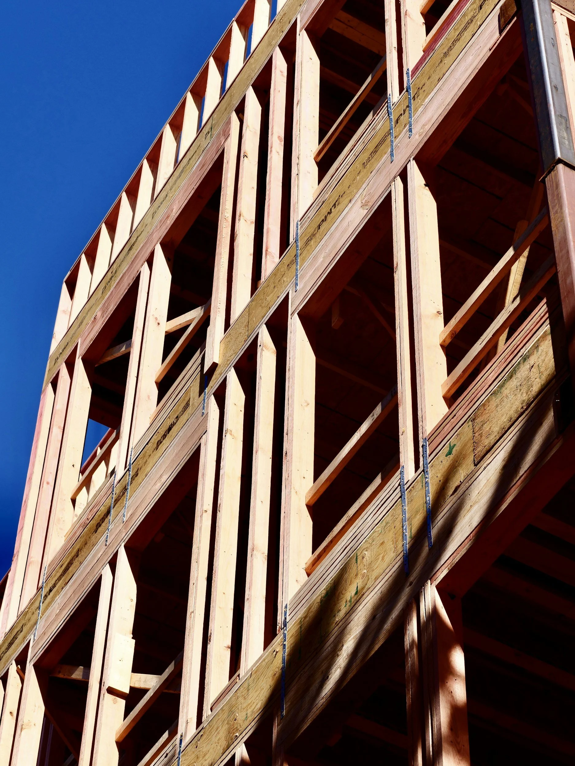 Wooden framing of a building under construction against a clear blue sky.