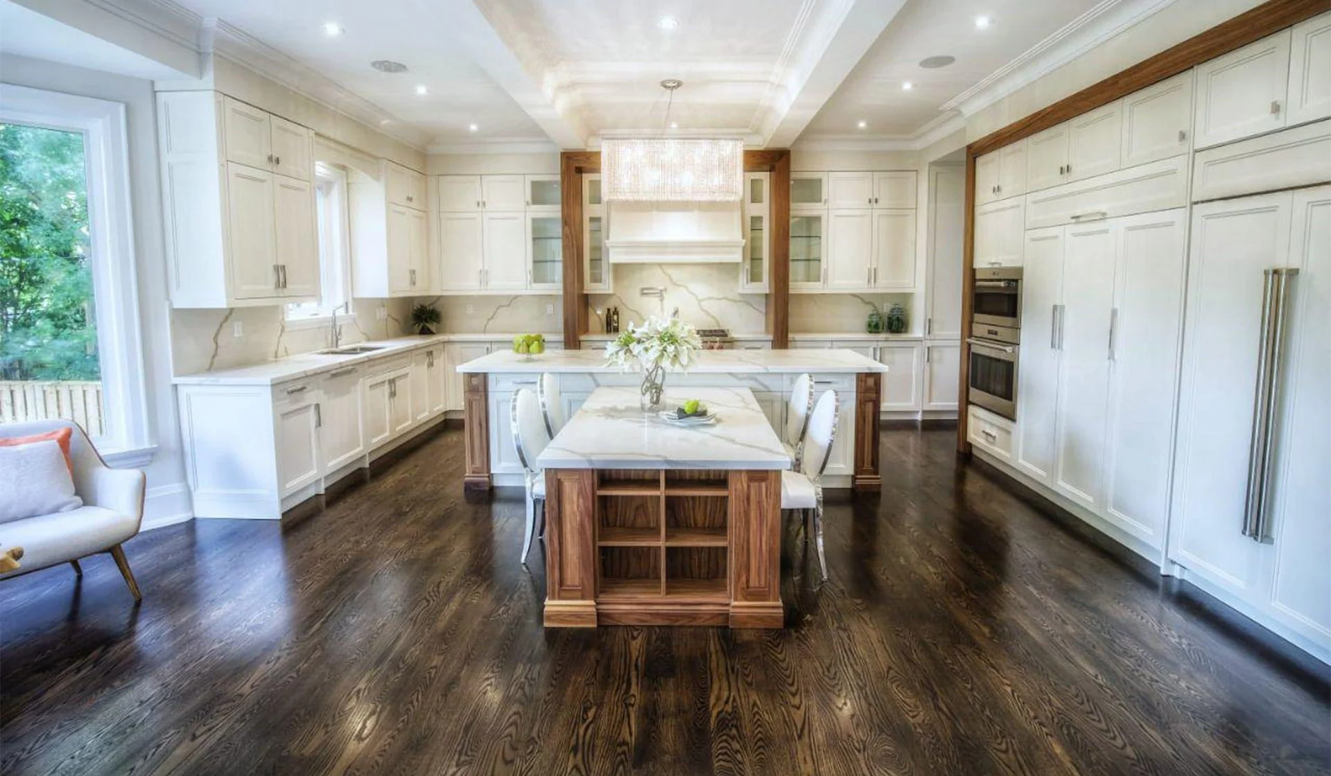 Modern kitchen with white cabinets, a large island with a marble top, and dark hardwood floors.