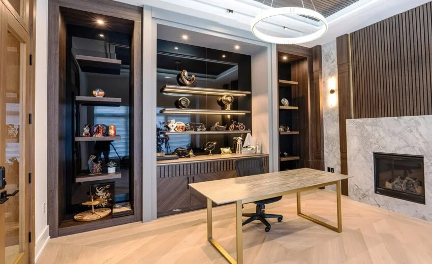 Modern office room with a desk, black chair, built-in shelves with decorative items, and a fireplace.
