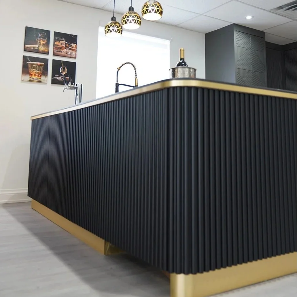 A modern kitchen island with a black and gold design, three hanging pendant lights above, a faucet, and a window in the background.