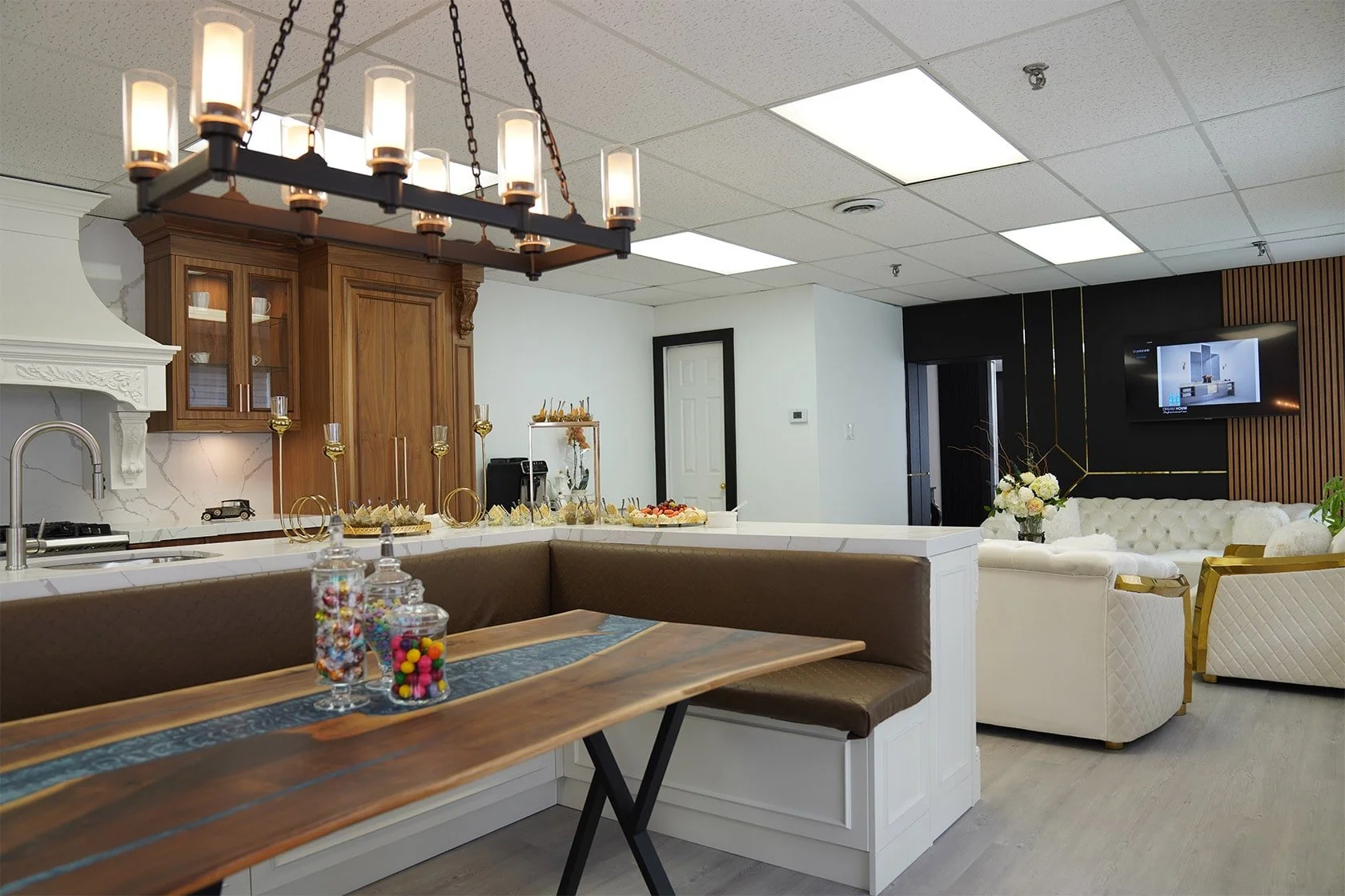 An interior living space with a kitchen and sitting area, decorated with flowers, candy jars, and modern furniture.