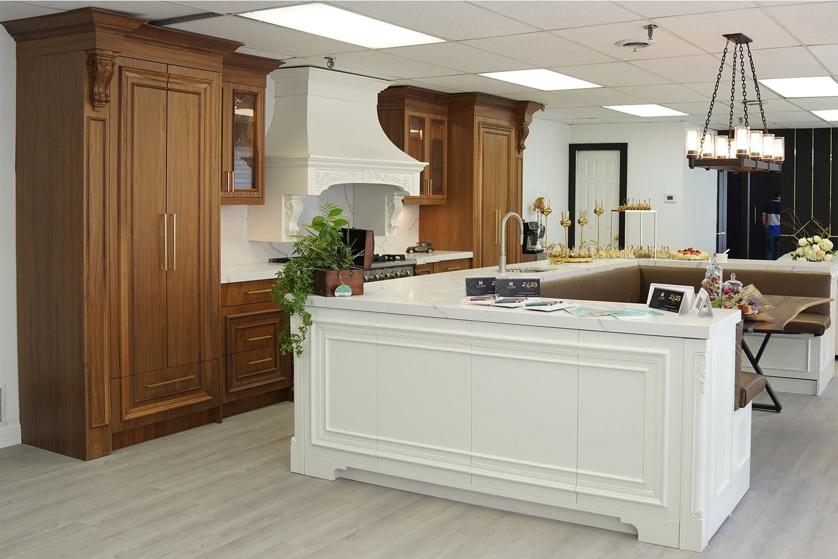 Kitchen with wooden cabinets, a white island with decorative molding, a chandelier, and various kitchen appliances and decorations.