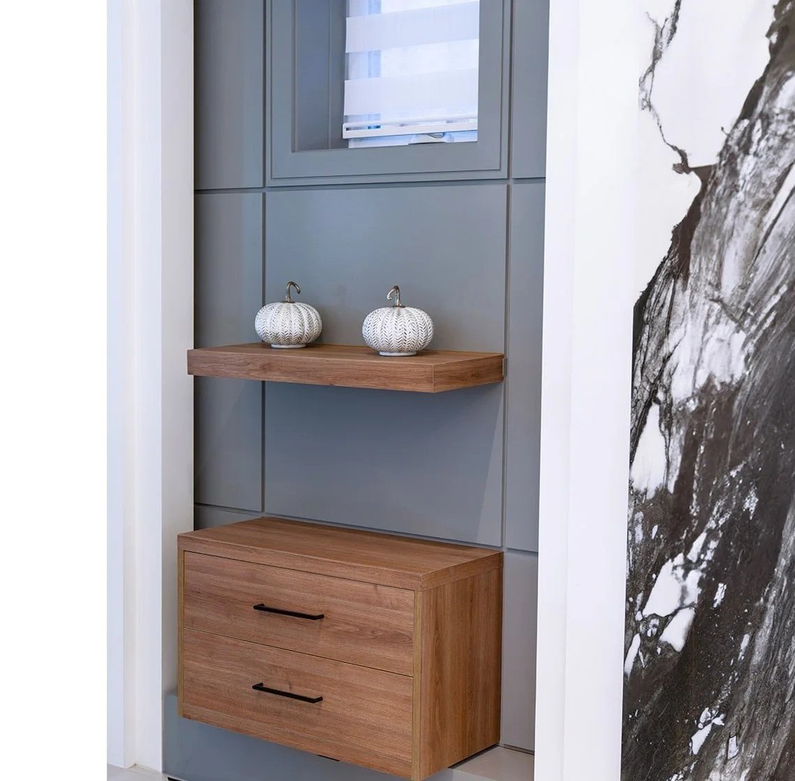 Decorative pumpkins on a wooden shelf against a blue wall with a partial mirror and black and white abstract artwork.