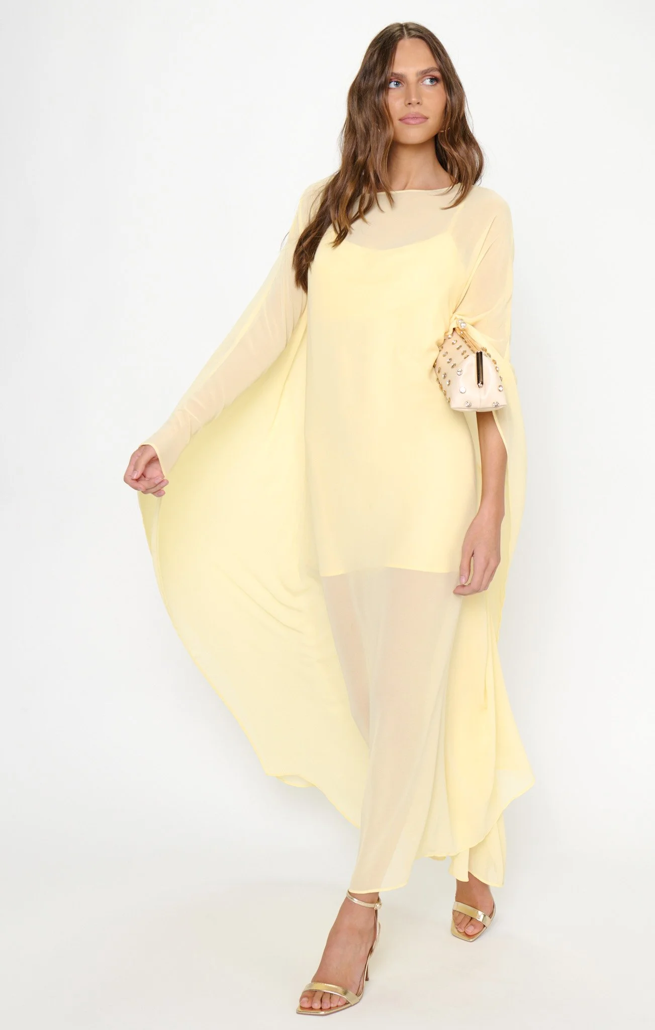 A woman in a yellow sheer dress with matching shoes and a small handbag.