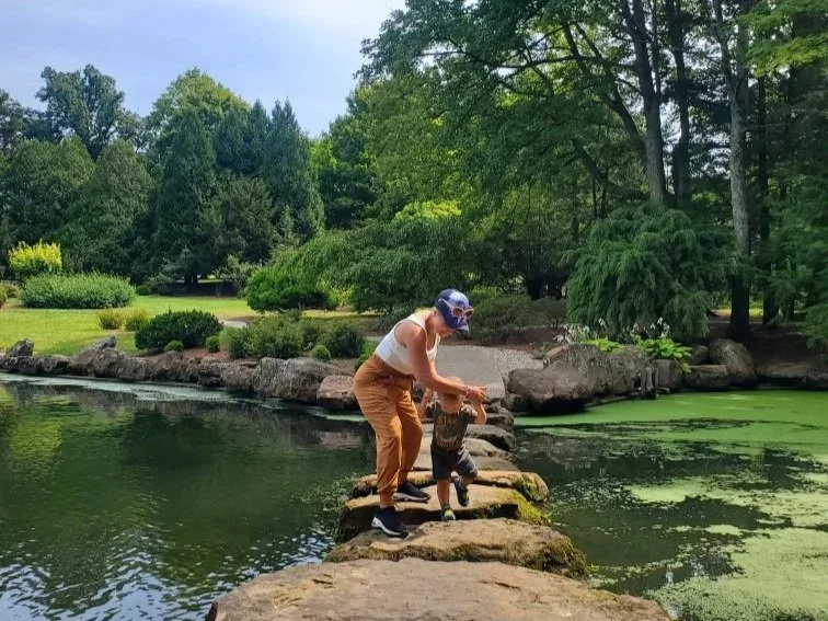Mandy helping her son across stepping stones in a creek