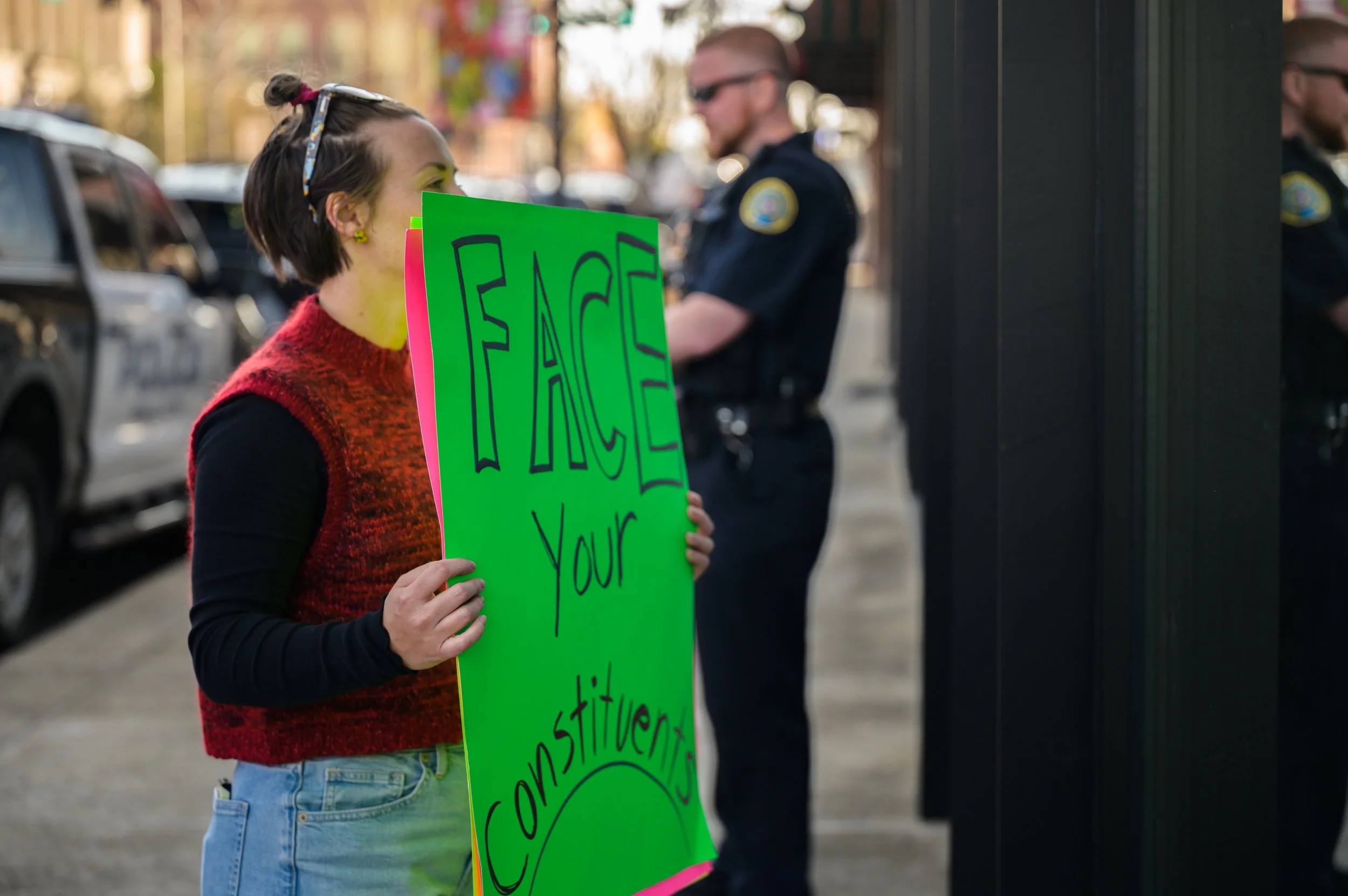 Mandy holding sign reading "Face Your Constituents"