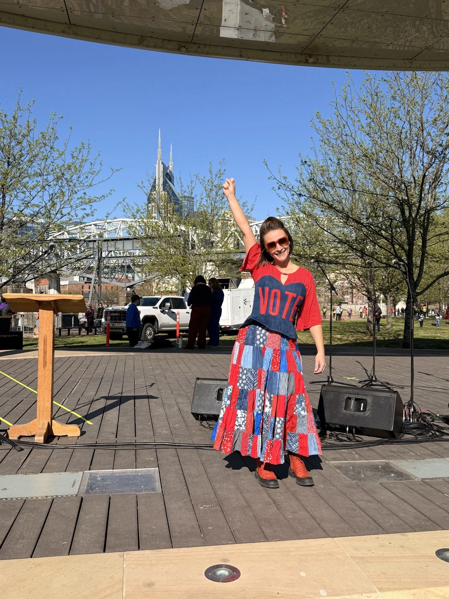 Mandy on stage with fist raised and Nashville skyline in the background