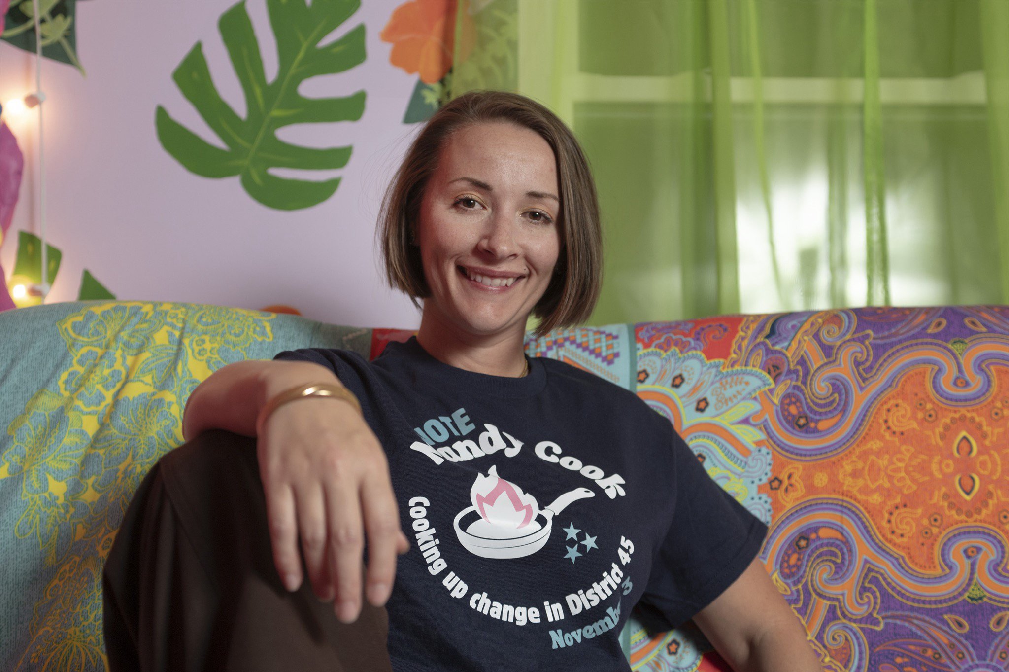 Mandy sitting on a couch, wearing her "Cooking up Change" shirt