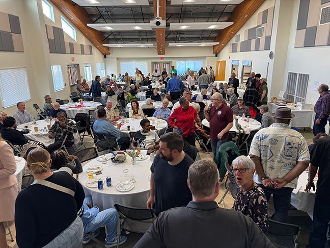 A diverse crowd, filling a banquet hall to capacity.