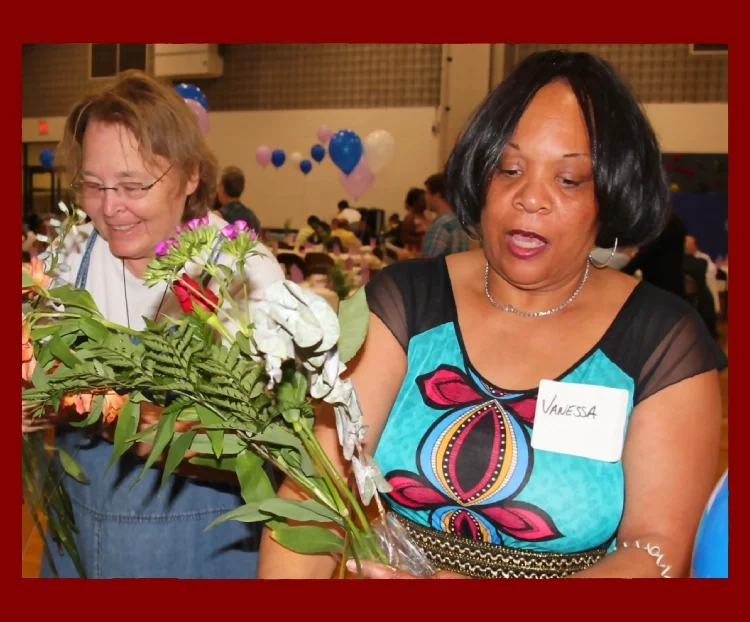 Two woman preparing cut flowers at an event