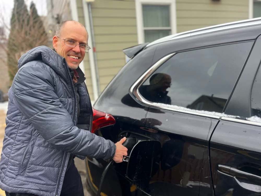 man plugging an electric car charger into a car