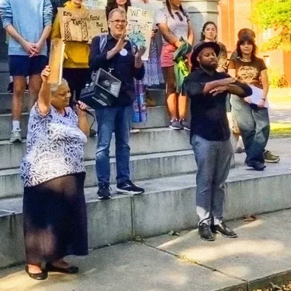 An older woman holding up a clipboard and a megaphone at a climate change protest rally