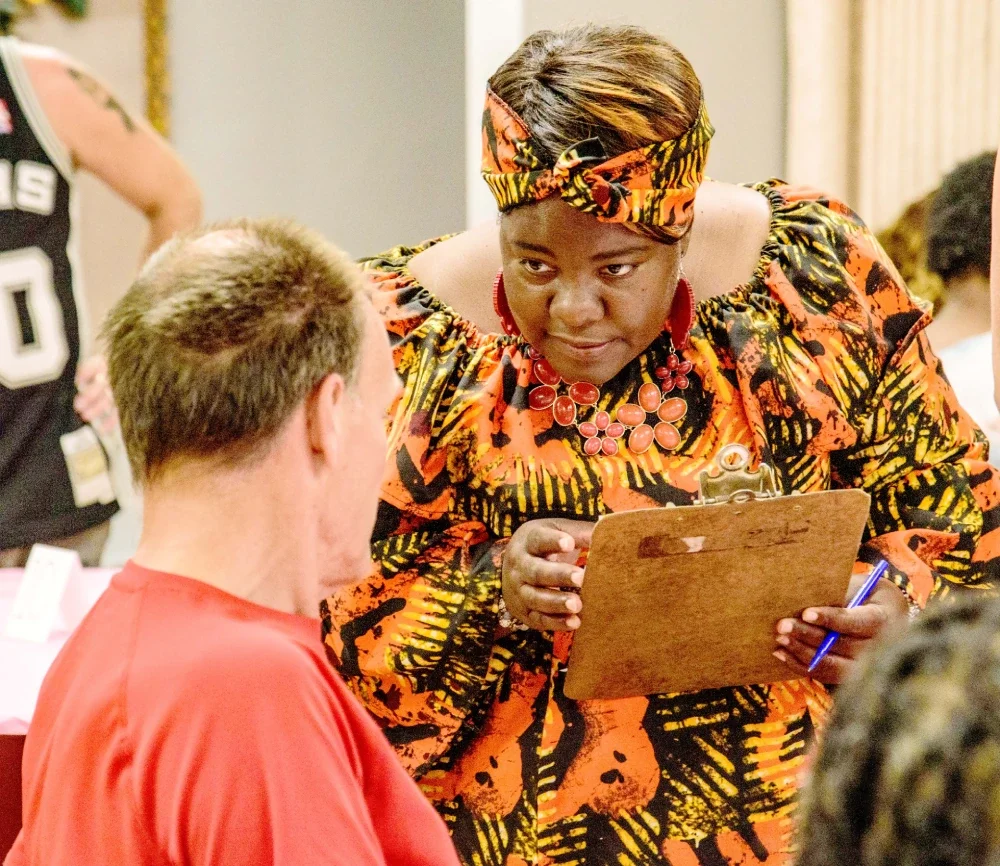 Volunteer with clipboard speaking to a man