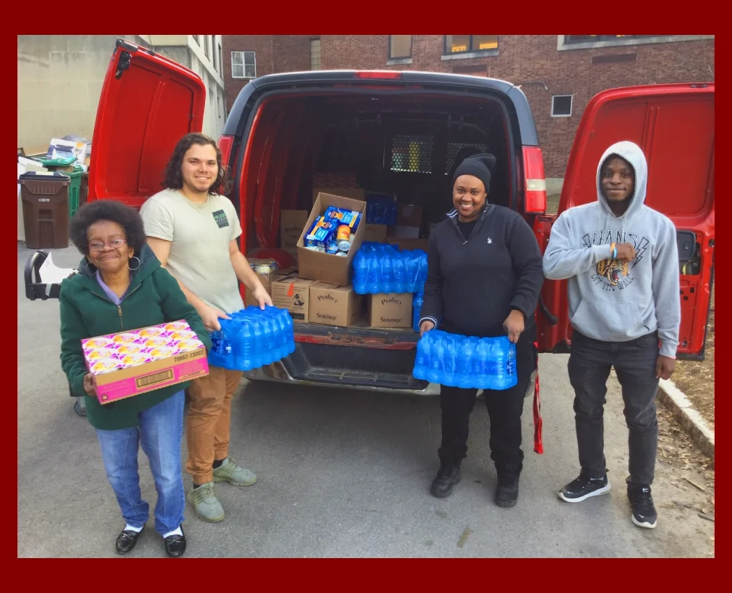 Four people unloading bottled water from a van