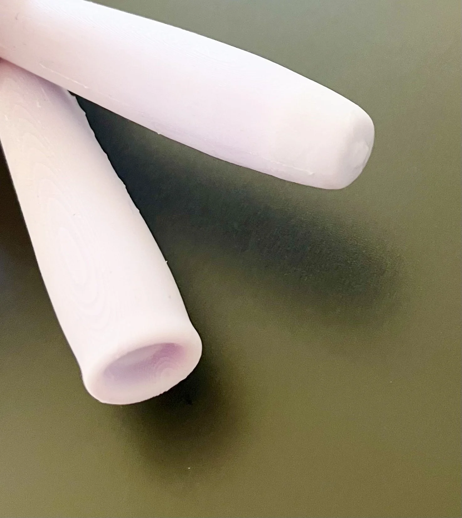 Close-up of two white objects with rounded ends resembling chalk or chalk-like sticks on a green surface.