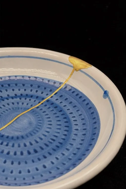 Close up of a small blue plate repaired with kintsugi.
