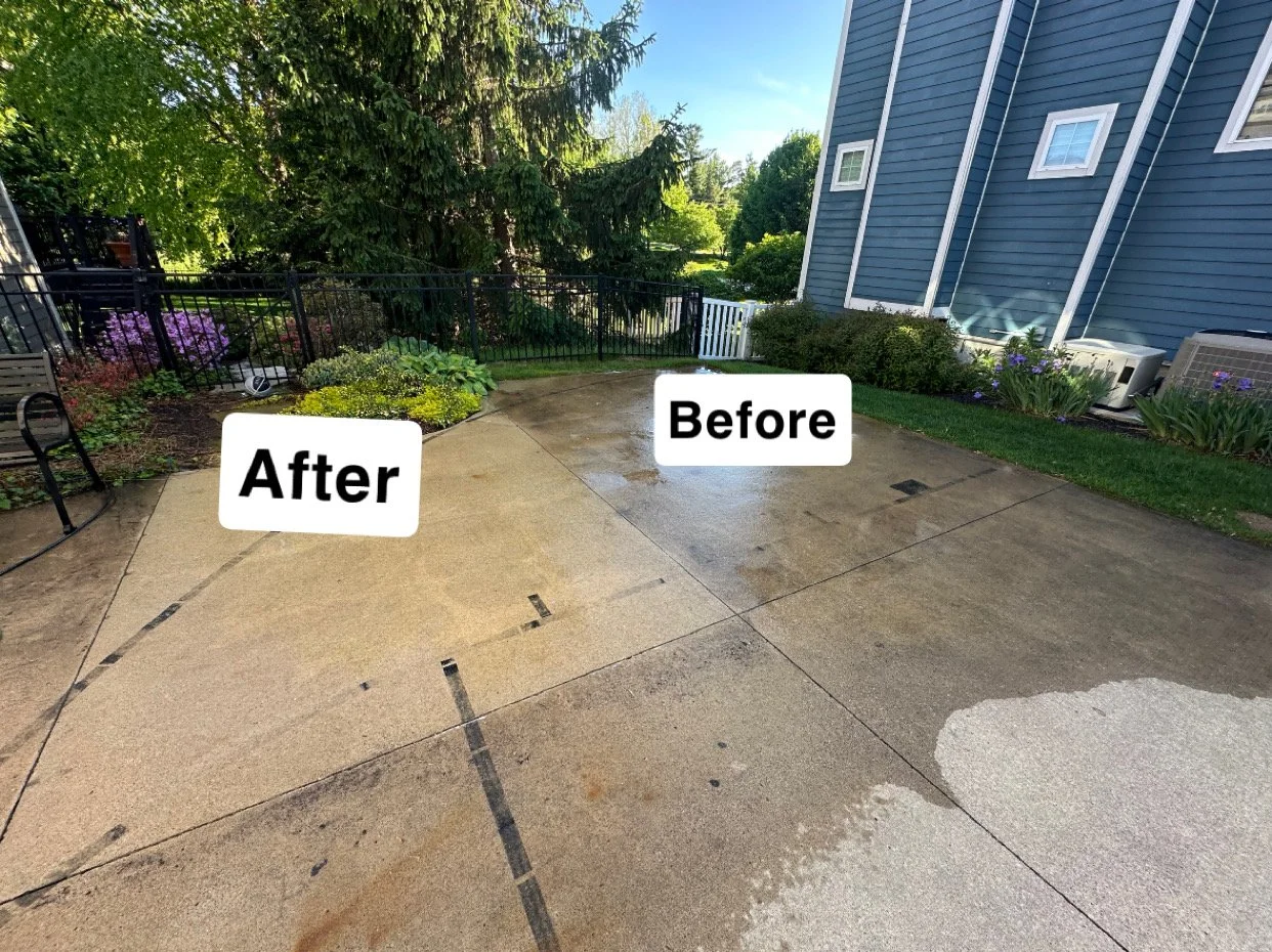 Cleaned and restored concrete patio area with a house and garden in the background, showing the difference between the before and after cleaning process.