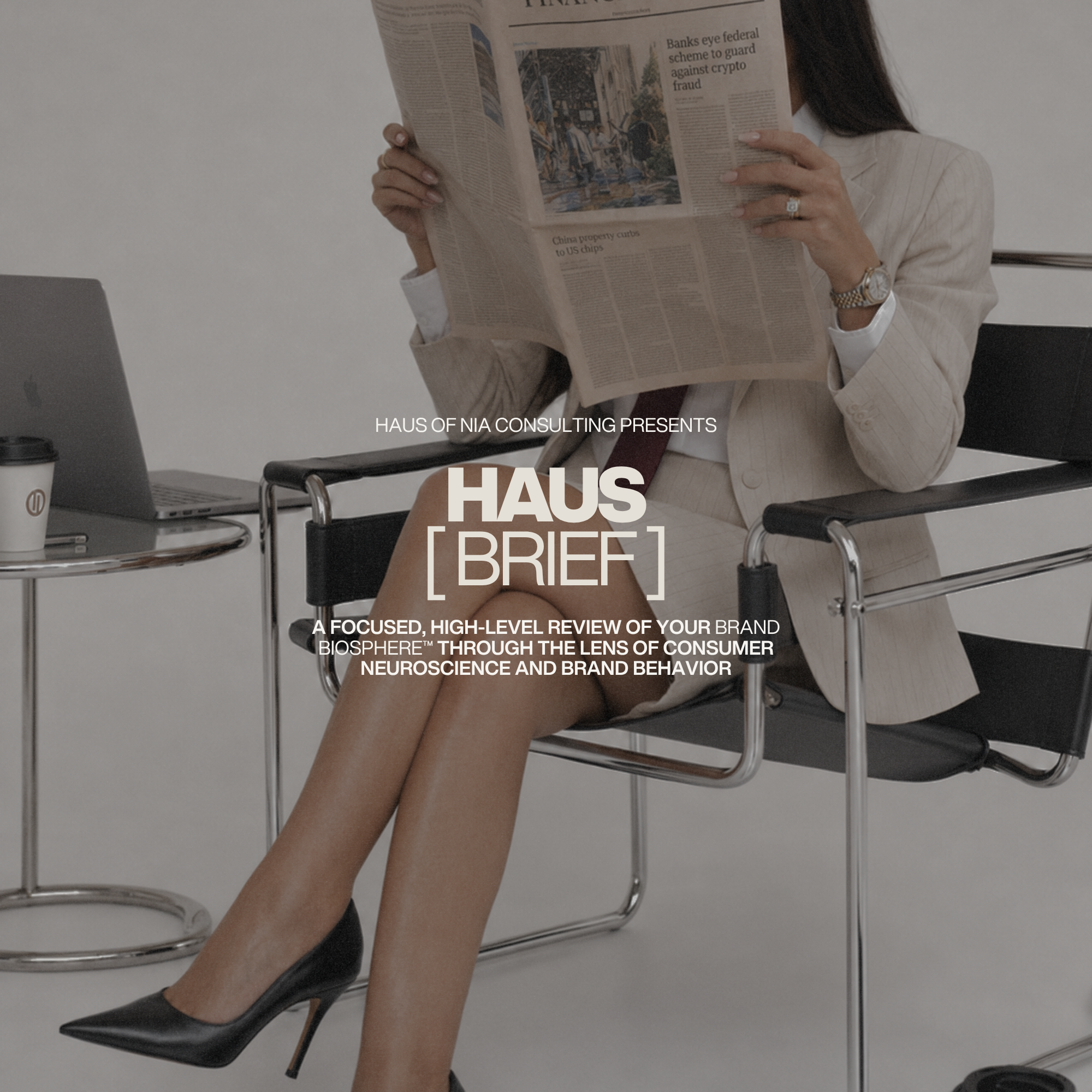 Nia, Founder & Managing Partner, Haus of Nia Consulting Brand Photoshoot - Nia sitting in a chair, wearing a beige suit and high heels, reading a newspaper in an office setting with a laptop and coffee cup on a glass table nearby.