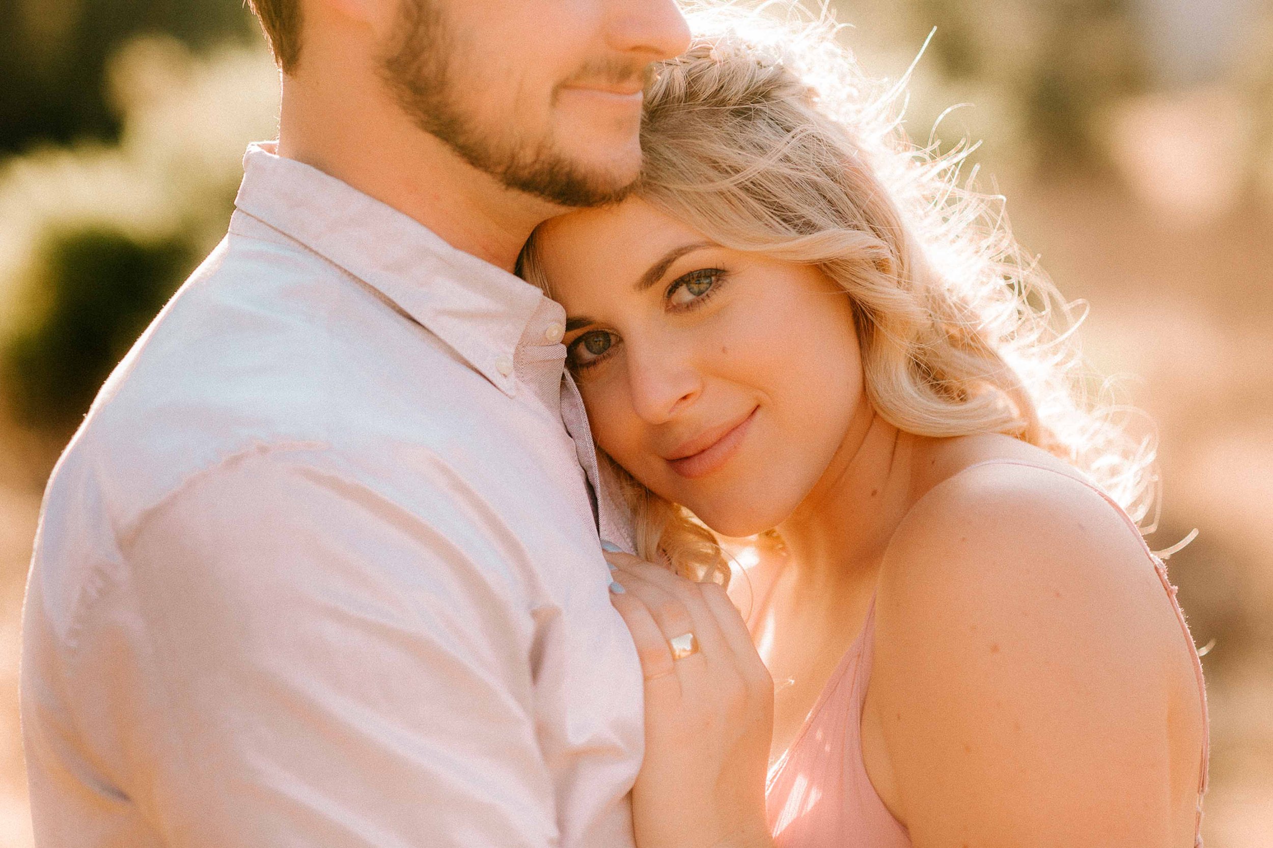 Caucasian couple posing for engagement photos with the woman looking at the camera