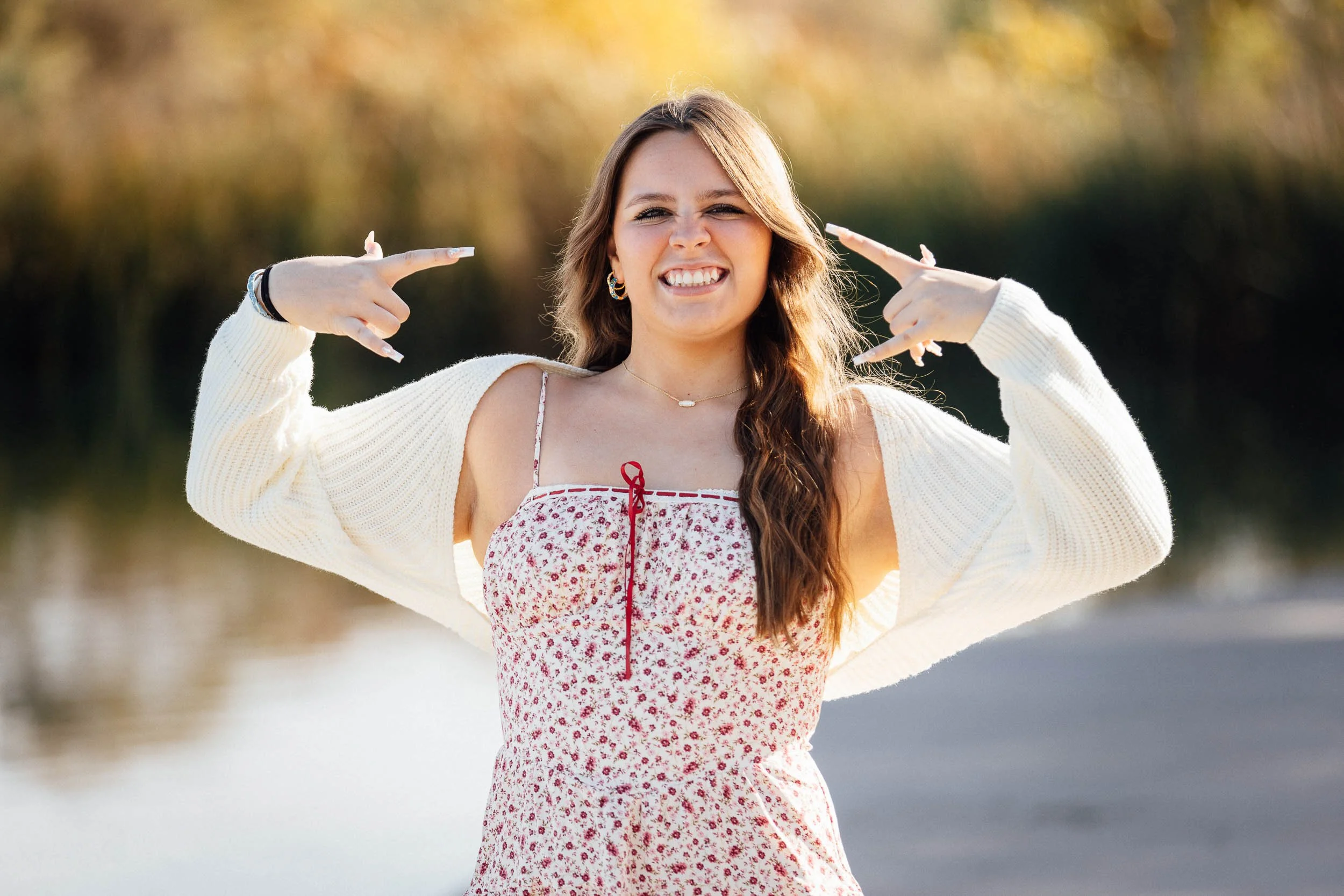 caucasian brunette in a park posing with hands for senior portraits