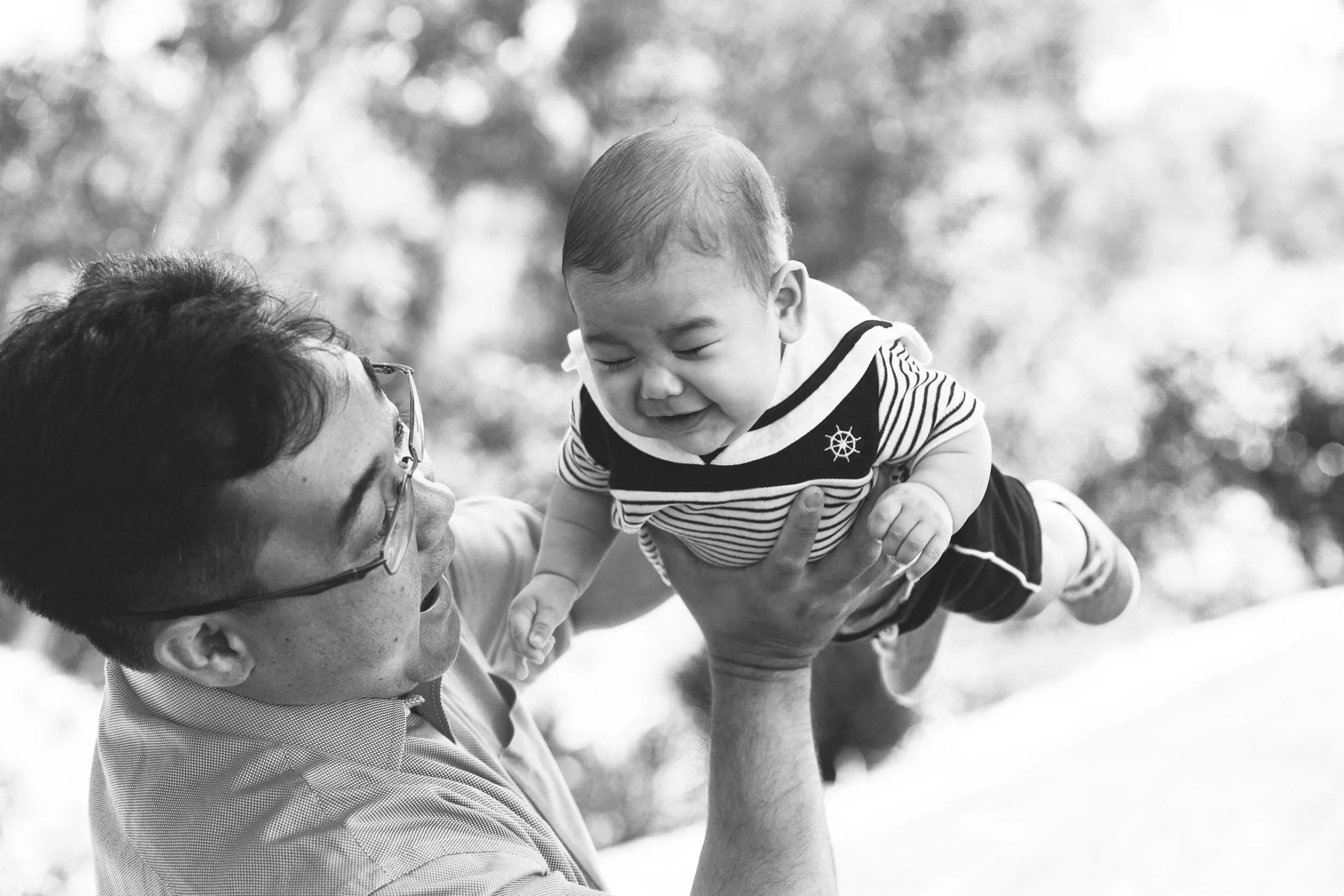 A father and son playing during a family portrait session in black and white.