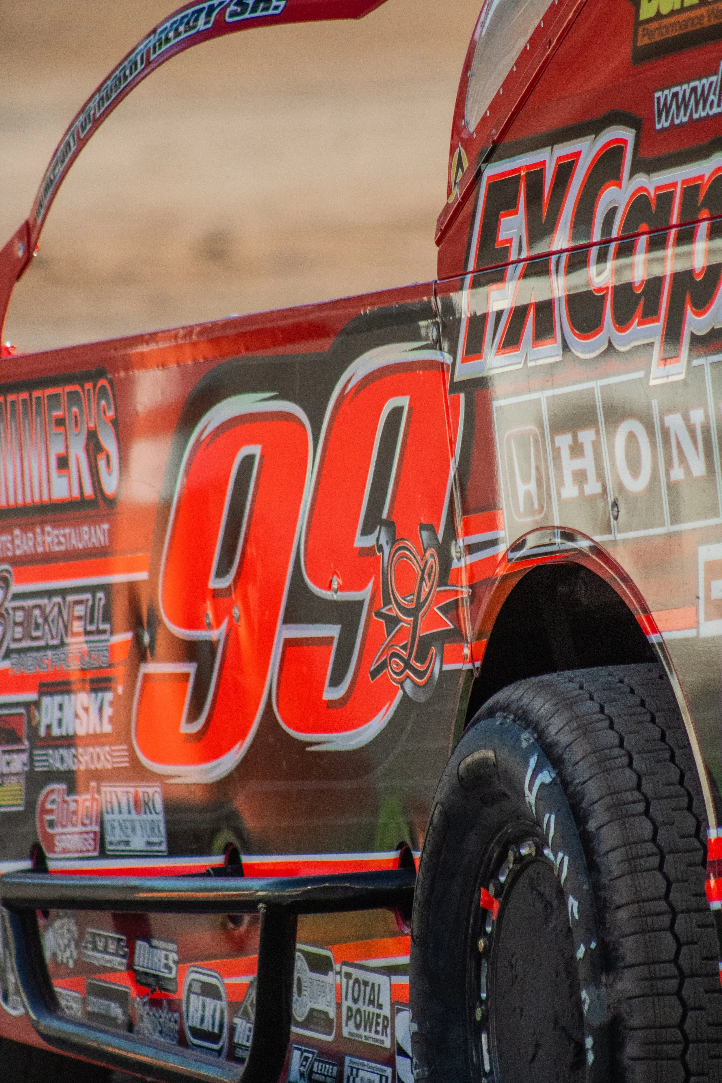 Close-up of a race car with the number 94 and various sponsorship logos and decals.
