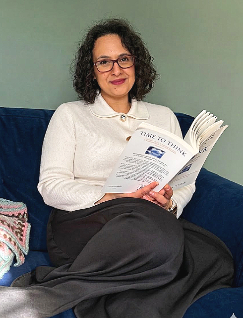 Lesley Keys Coach.  A woman with curly black hair, glasses, and a white sweater sitting on a blue couch, reading a Nancy Kline book titled 'Time to Think'.