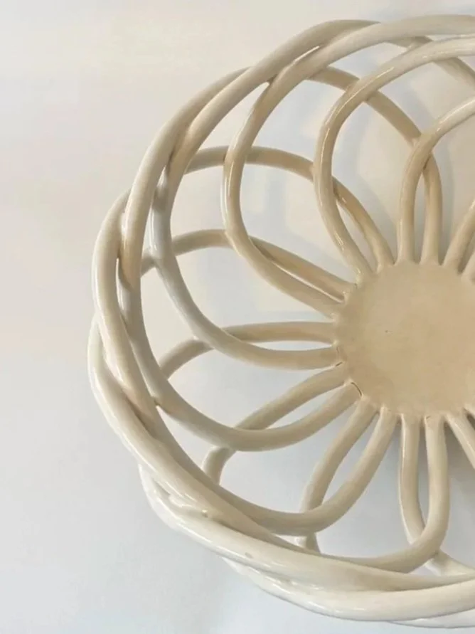 Close-up of a beige decorative round wicker or rattan basket with an open, intricate design.