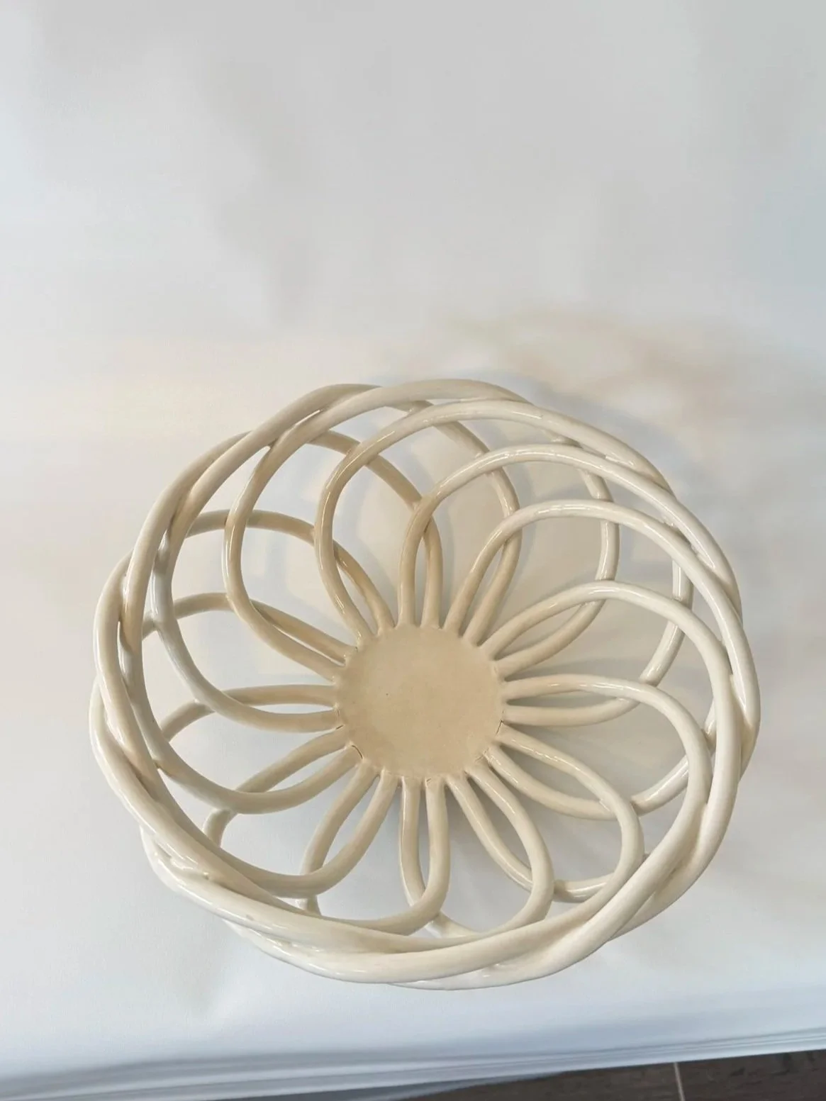 A white decorative wire sphere with a flower-like design and a solid circular base.