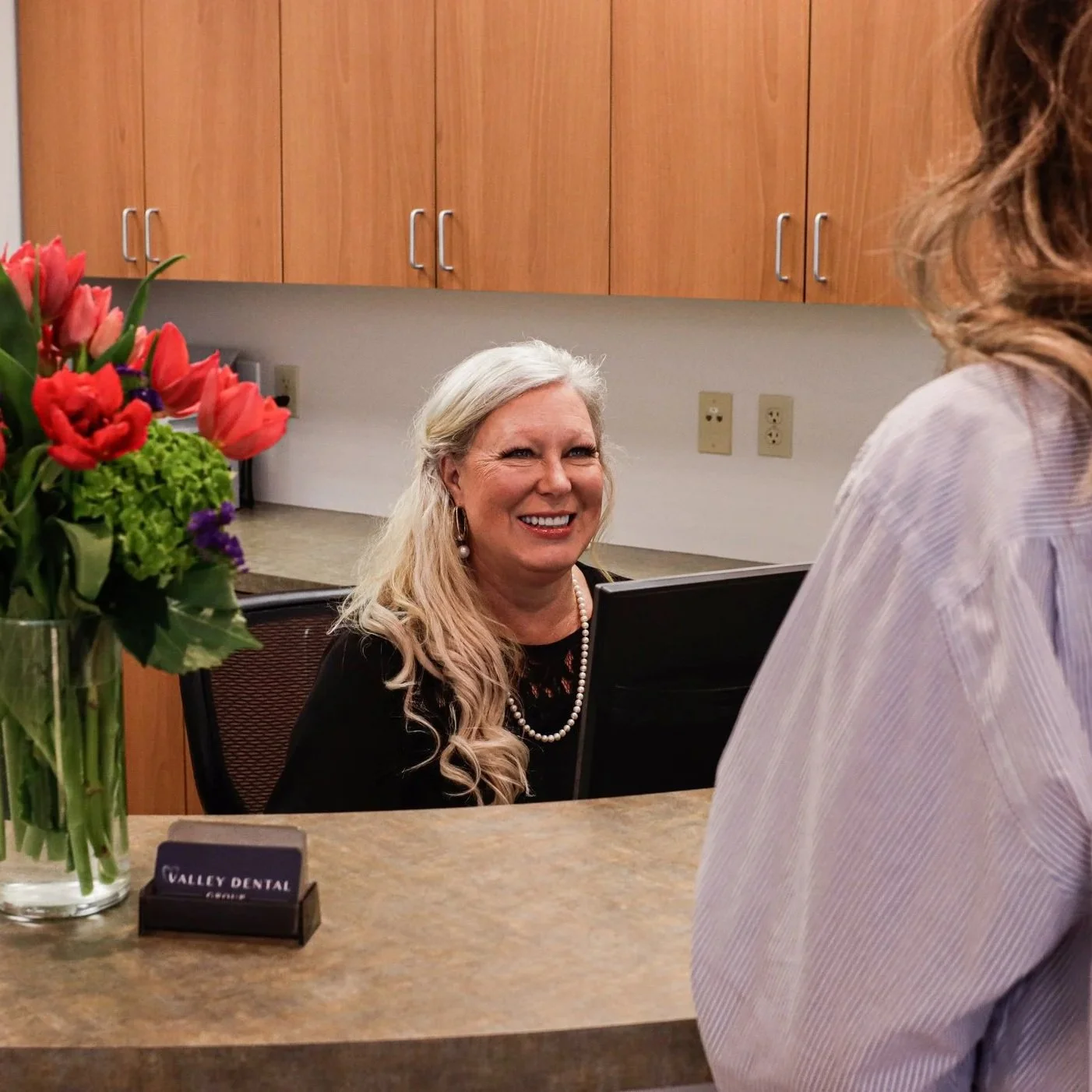 Friendly dental office receptionist welcoming a patient at a Phoenix AZ dental practice