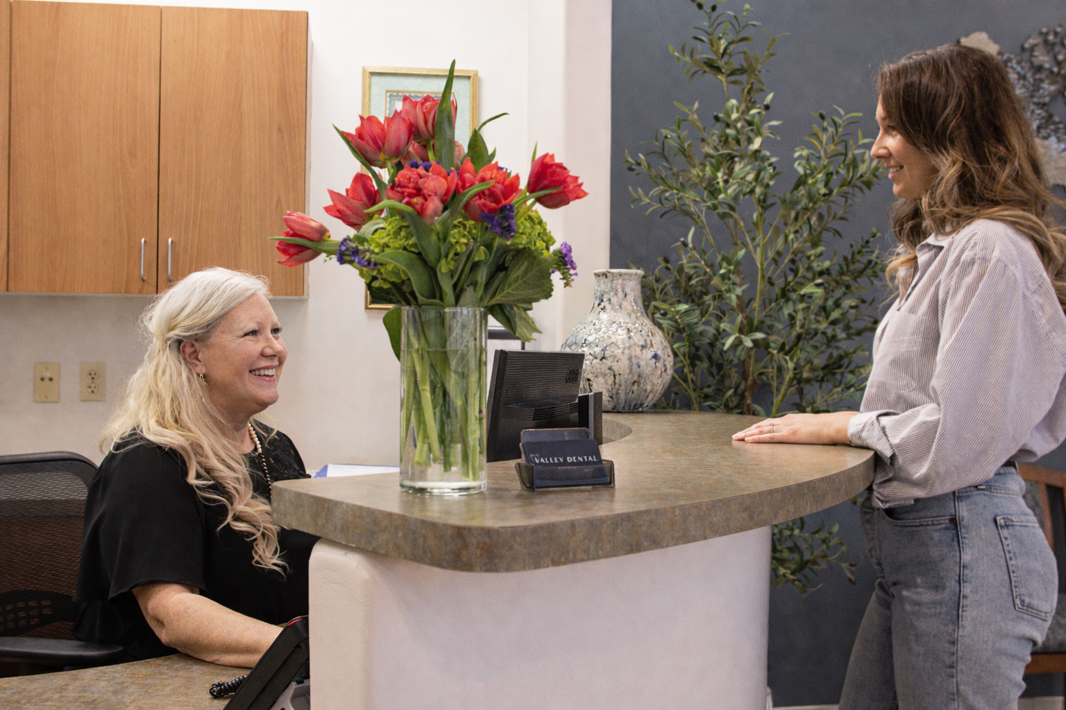 Patient speaking with a dental receptionist at the front desk of a Phoenix Arizona dental office.