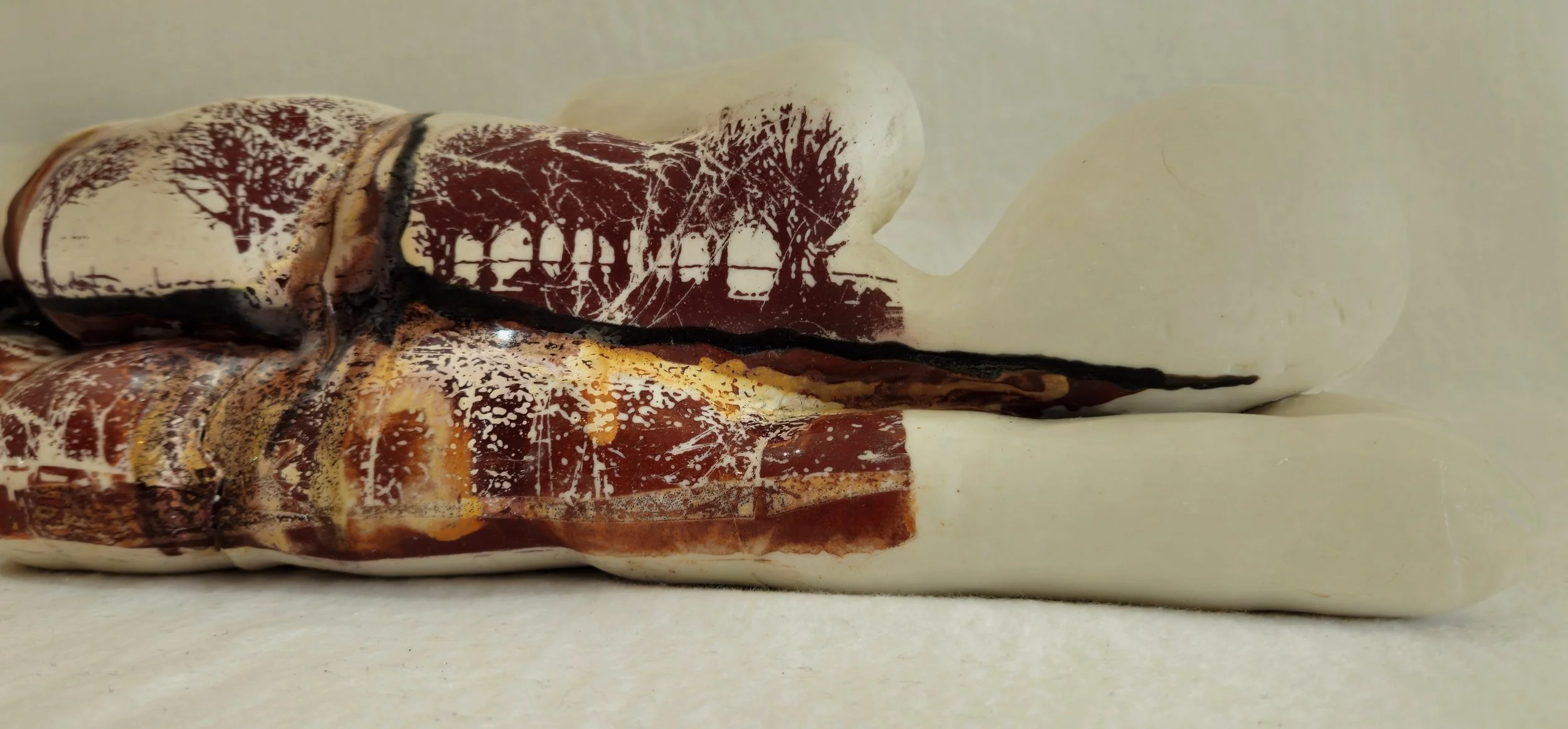 Close-up of a marble sculpture depicting a seated figure, with detailed trees and landscape engravings on the surface.