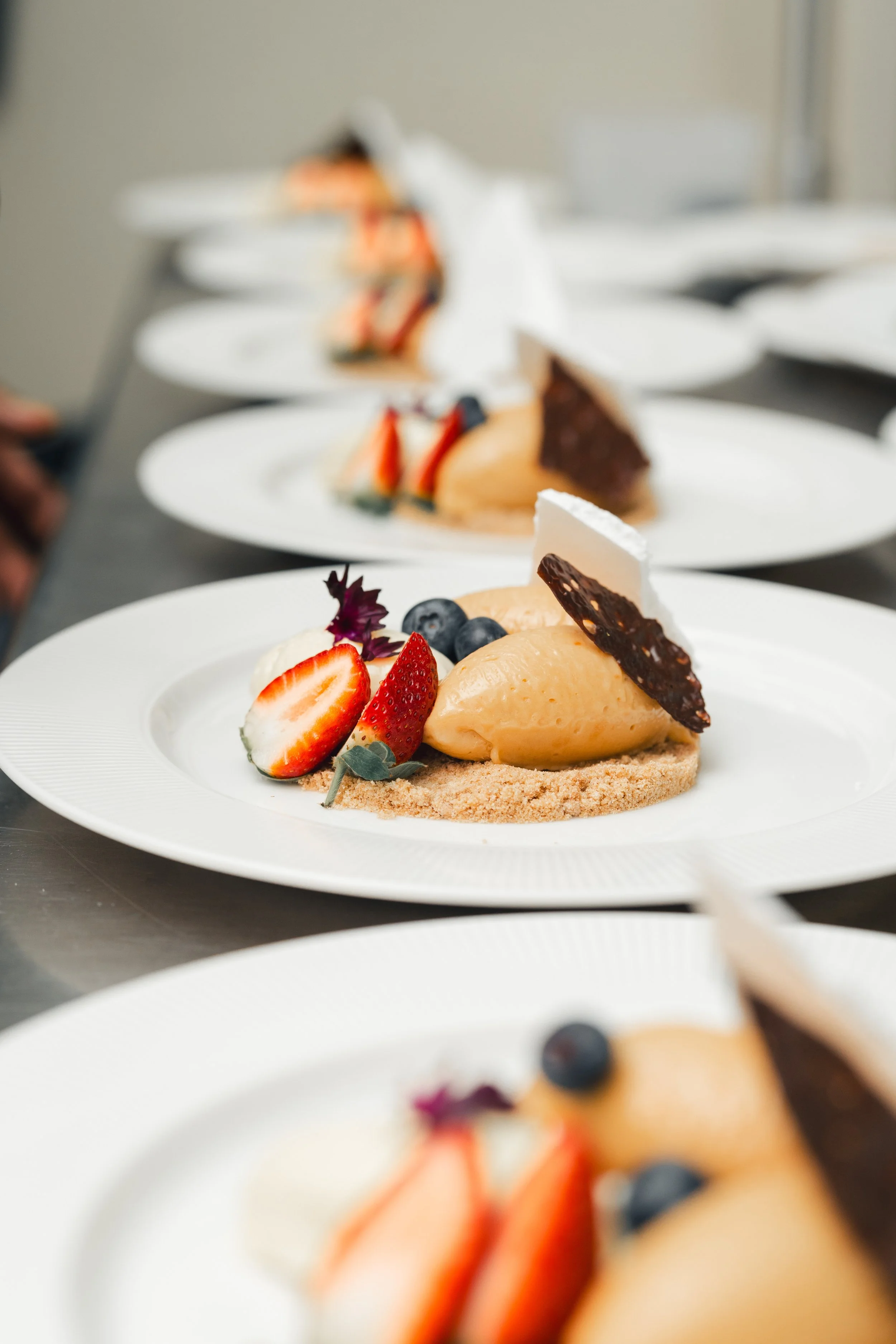 Pastry dessert with strawberries, blueberries, and decorative chocolate on a white plate.
