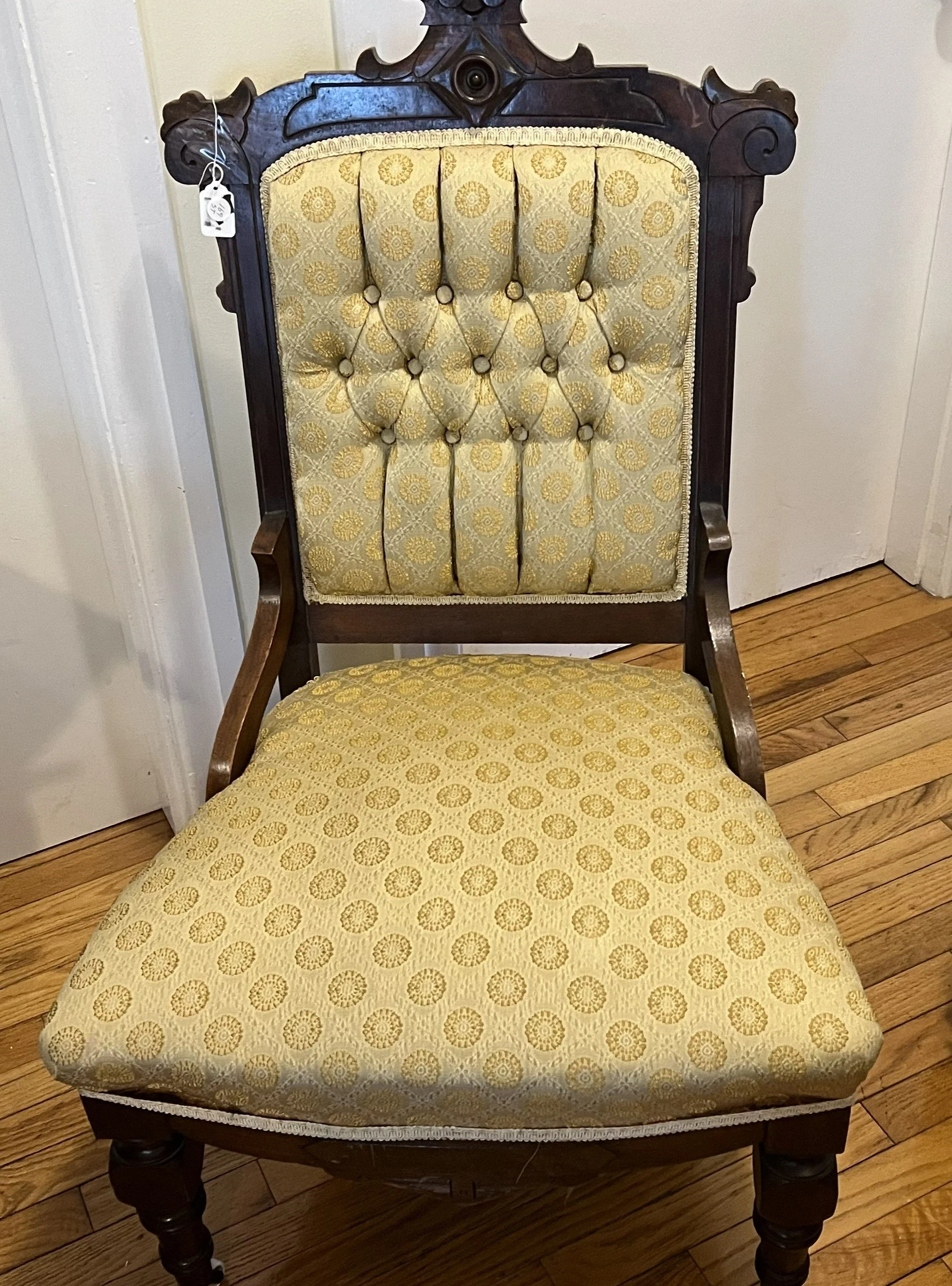 Victorian Eastlake style parlor chair featuring a carved wood frame and yellow tufted upholstery. Eastlake, characterized by machine-carved geometric or floral motifs and a less heavy appearance than earlier Victorian styles. 
Manufactured in the lat