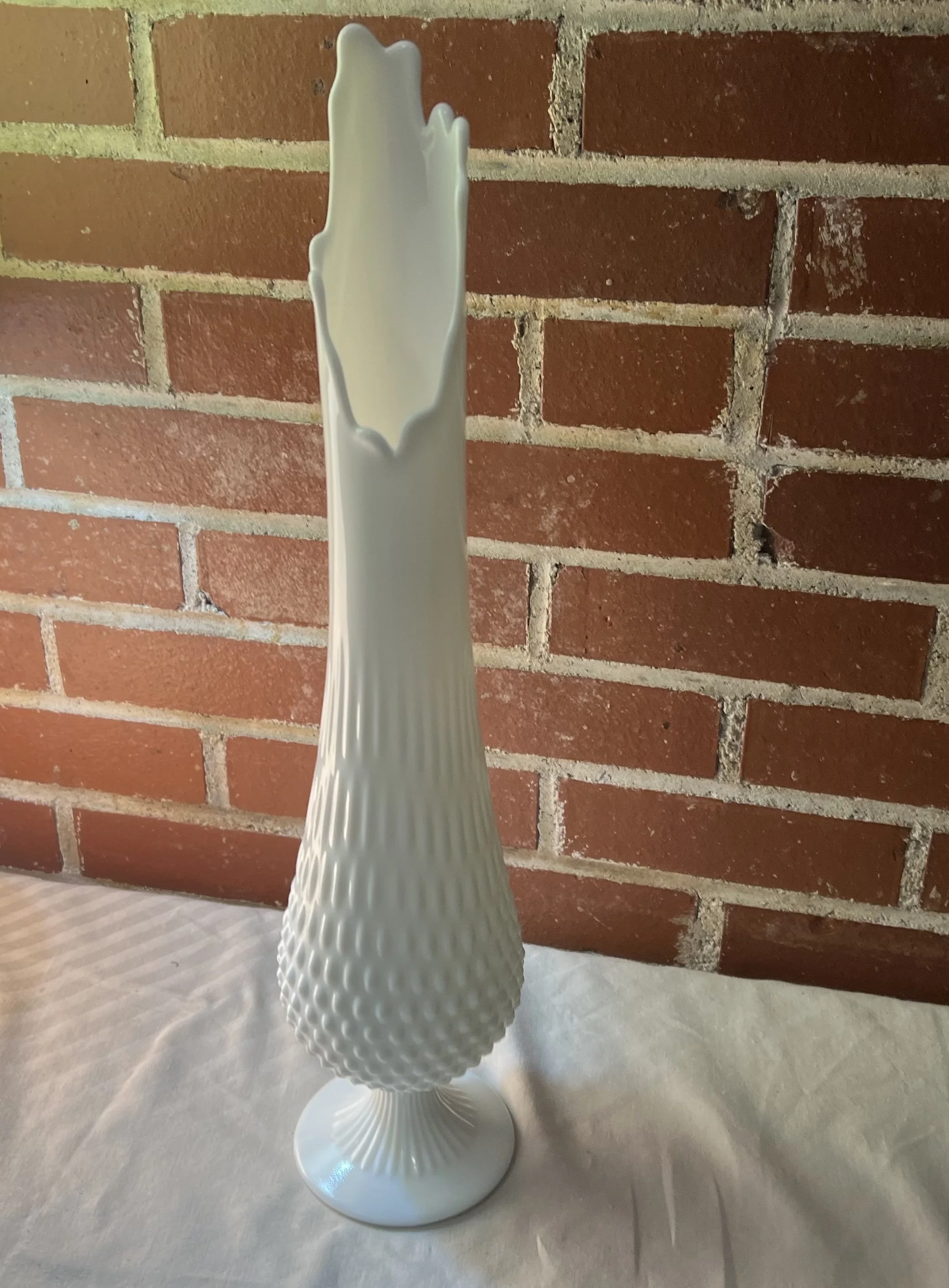 Vintage Fenton Hobnail white milk glass pedestal swung vase, produced during the 1950s or 1960s. 
by the Fenton Art Glass Company.
This is a hobnail pattern with a fluted, swung mouth and pedestal base.
Color: Opaque white milk glass.