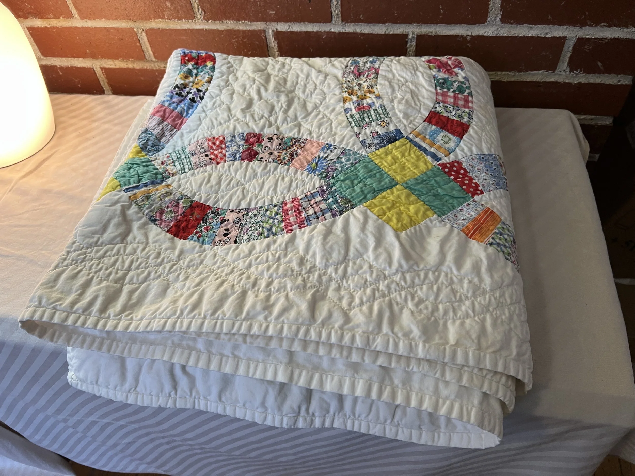 Vintage Double Wedding Ring pattern quilt, often featuring fabrics like feed sacks from the early to mid-20th century. 
Pattern: Double Wedding Ring, prized by collectors and traditionally made as a wedding gift. 
Design: Interlocking rings pieced fr