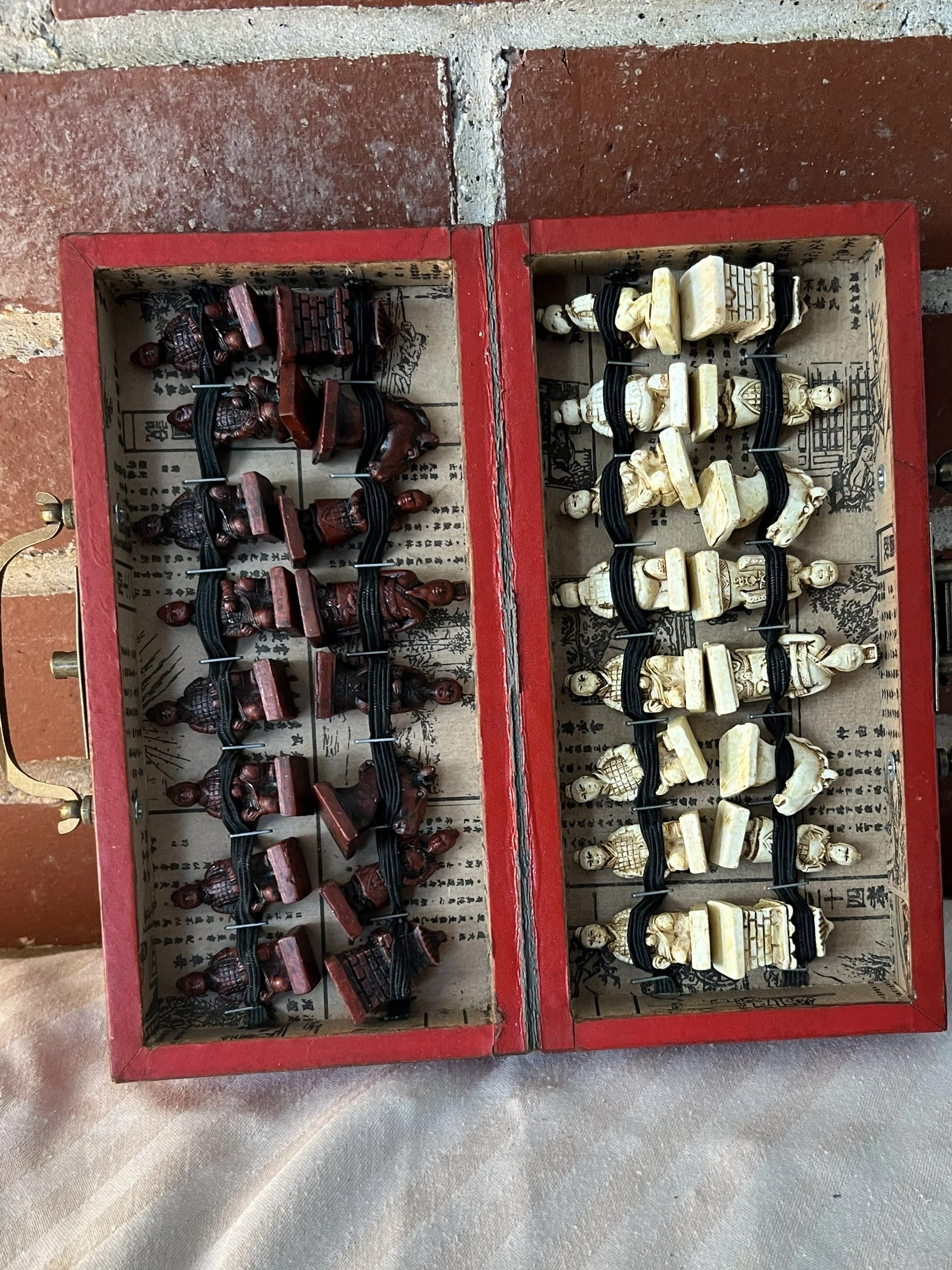 A wooden chess set with carved wooden chess pieces in a red box