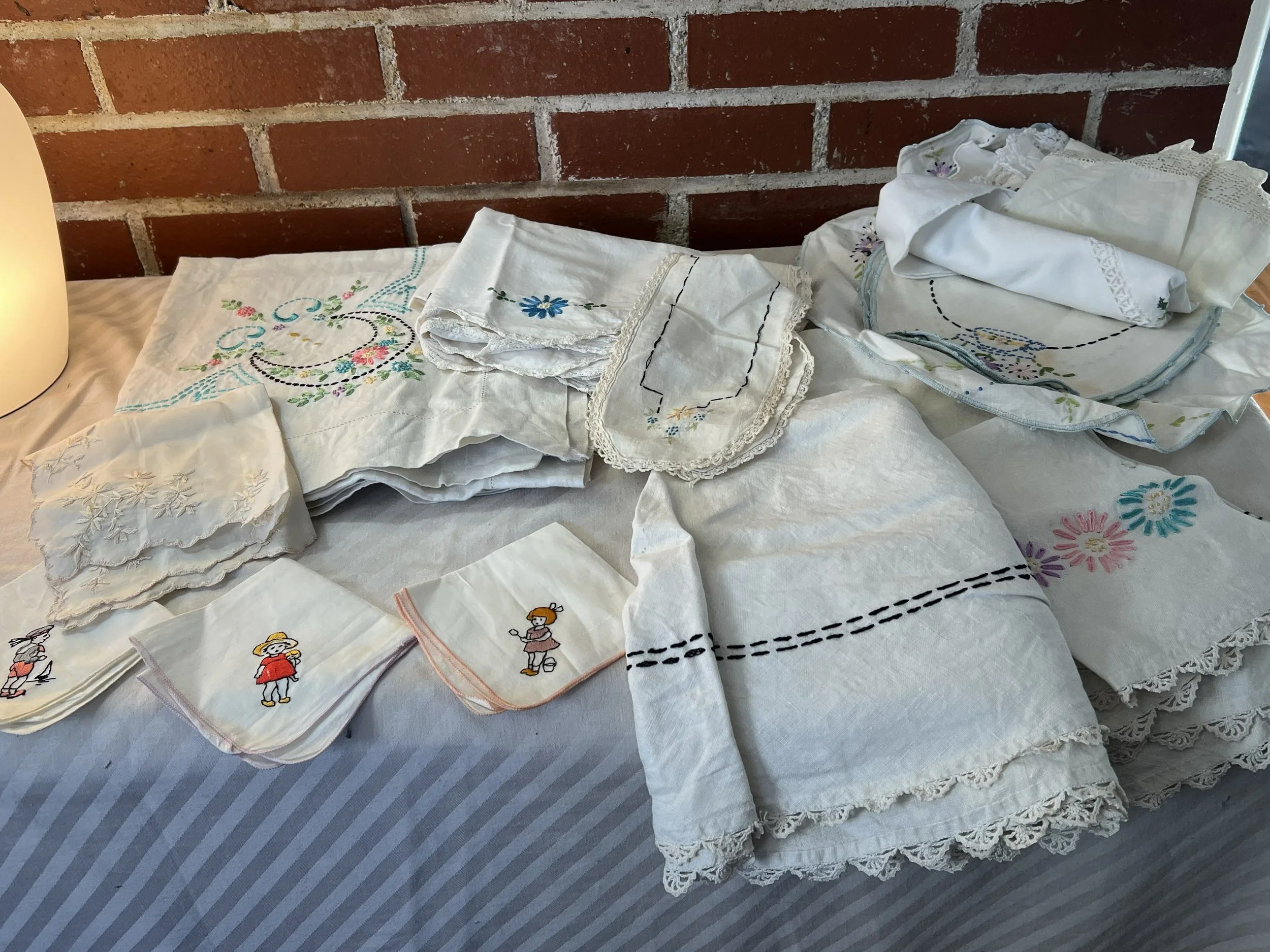 A collection of embroidered and embroidered cloth napkins, handkerchiefs, and linens with floral and character embroidery, 